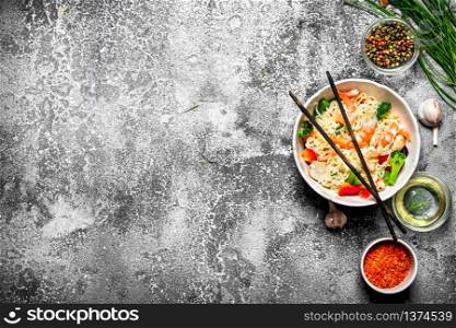 Asian food. Chinese noodles with vegetables and shrimp. On an old rustic background .. Asian food. Chinese noodles with vegetables and shrimp.