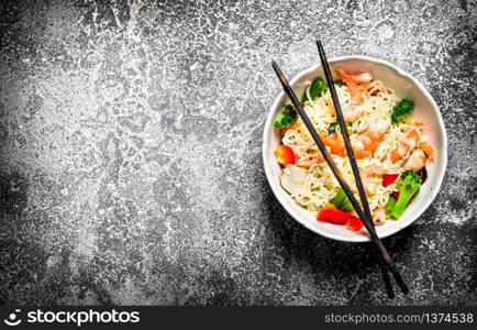 Asian food. Chinese noodles with vegetables in a bowl . On an old rustic background .. Asian food. Chinese noodles with vegetables in a bowl .