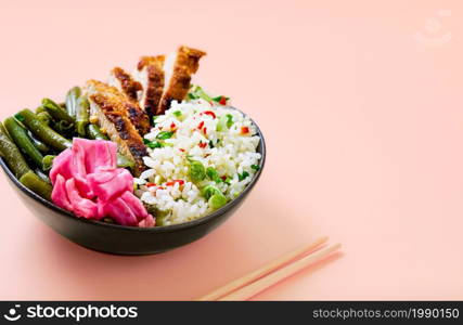 Asian food idea. Rice with spices and turkey wedges in a black bowl with sauteed green beans, hot peppers, fermented cabbage. Close-up with copy space