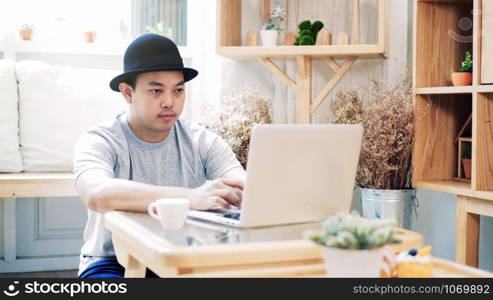 Asian freelance in casual suit sitting to work with technology laptop in modern co-working space, couple and colleague concept