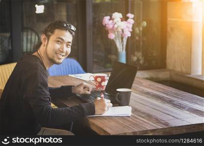 asian freelance man write on paper with computer laptop on working table