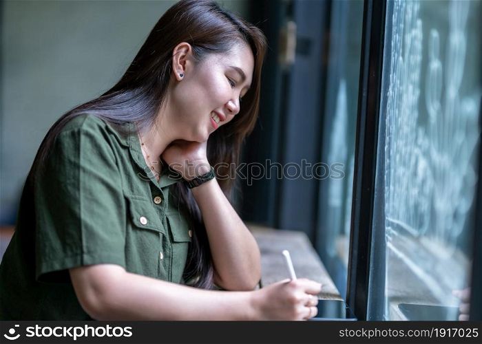 asian freelance people business female casual working taking note on digital tablet with electronic pen with laptop computer with coffee cup in coffee shop like the background,communication concept