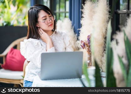 asian freelance people business female touching massaging stiff neck after working with laptop computer with coffee cup and smartphone felt like relaxing in coffee shop like the background