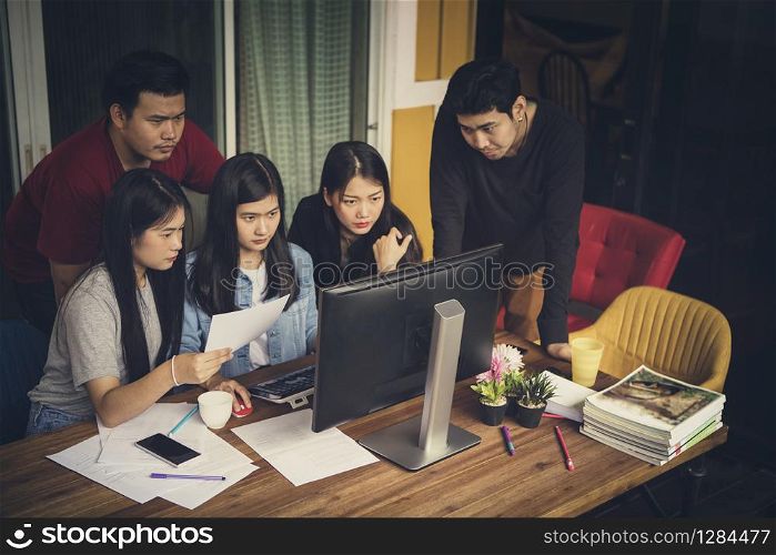 asian freelance team looking to office computer with seriously face