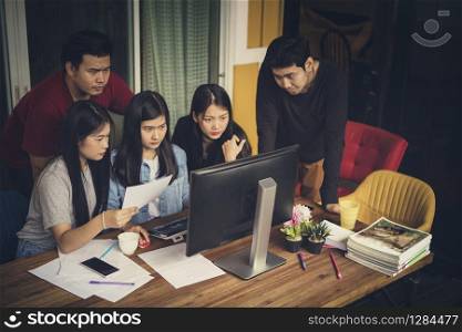 asian freelance team looking to office computer with seriously face