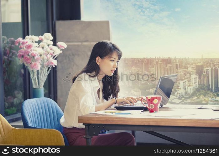 asian freelancer working on computer laptop against urban office building background