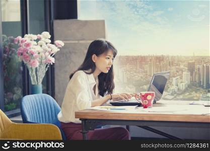 asian freelancer working on computer laptop against urban office building background