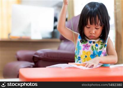 Asian girl child sewing in living room at home as home schooling while city lockdown because of covid-19 pandemic across the world. Home Scholling prepare for Preschool concept.