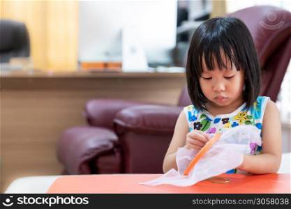 Asian girl child sewing in living room at home as home schooling while city lockdown because of covid-19 pandemic across the world. Home Schooling prepare for Preschool concept.