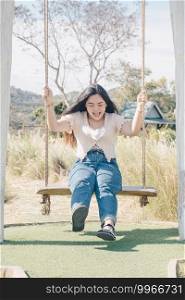 Asian girl enjoy sit on swing outdoor at cafe with nature.