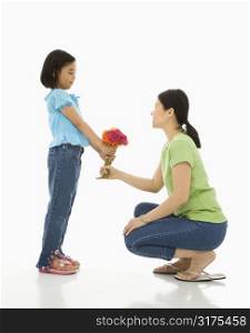Asian girl handing bouquet of flowers to her mother.