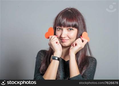 Asian girl is holding two paper heart by both side of her head