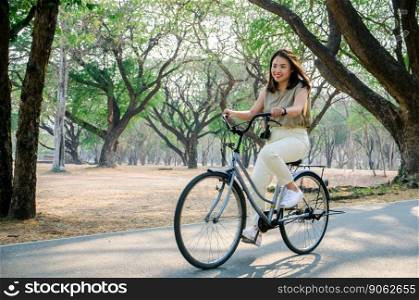 asian girl is riding bicycle on road in park with smile face