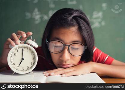 Asian girl is sleeping at the desk in the classroom, The little girl wearing glasses clutches after falling asleep in class.