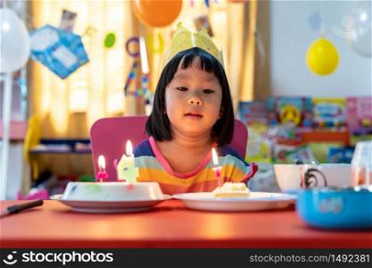 Asian girl kid with her birthday cake celebrate alone with family because city lockdown while COVID-19 Pandemic. Celbration and quarantine concept.