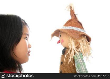 Asian girl looking her scarecrow toy isolated on white