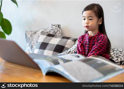 Asian girl or daughters use notebooks and technology for online learning during school holidays and watching cartoons at home. Educational concepts and activities of the family