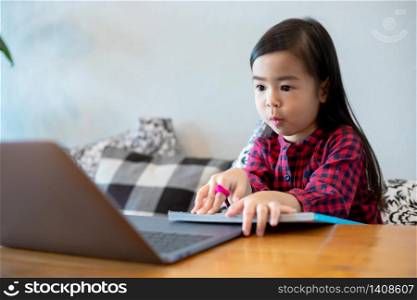 Asian girl or daughters use notebooks and technology for online learning during school holidays and watching cartoons at home. Educational concepts and activities of the family