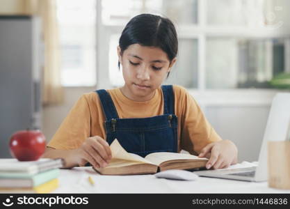 Asian girl reading and doing homework at her home. Education and self learning concept.