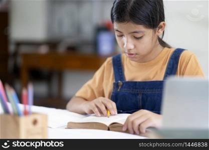 Asian girl reading and doing homework at her home. Education and self learning concept.