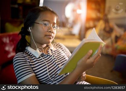 asian girl reading school book in home liviing room