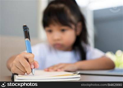 Asian girl student holding a pen for taking notes and doing homework and using the laptop for online learning class at home, Education and distance learning for children Homeschooling concept