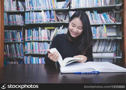 Asian girl students reading books and using notebook in the library.