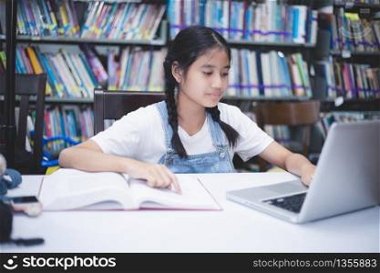 Asian girl students reading books and using notebook in the library.