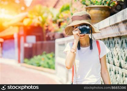 Asian girl teen tourist taking a nature photo travel while walking with hat and backpack bag