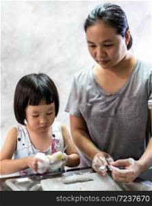 Asian girl washing dish and tableware with her mom, housework for child make executive function for kid. Houseworking for kid lifstyle and family concept.