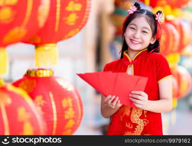 Asian girl wearing red traditional Chinese cheongsam decoration holding red envelopes in hand and lanterns with the Chinese text Blessings written on it Is a Fortune blessing for Chinese New Year