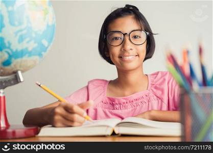 Asian girl with glasses is taking notes in her class notebook, Educational concept