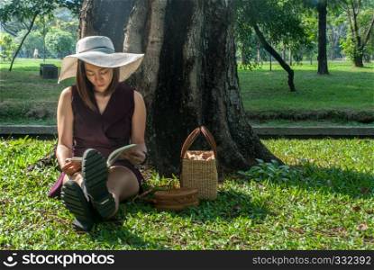 Asian girls are reading a book at the park in the afternoon of summer in Bangkok.