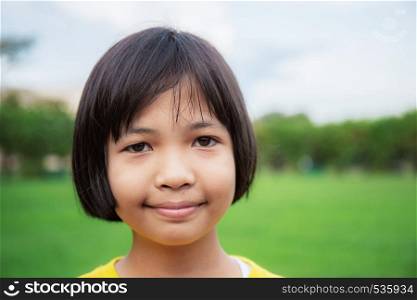 Asian girls are smiling on lawn in park with sky.