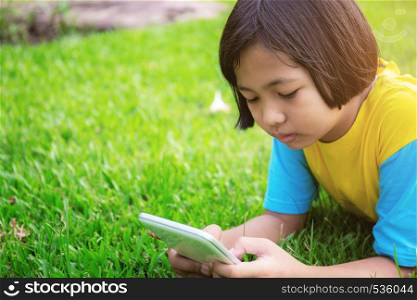 Asian girls are using tablet on lawn in the park.