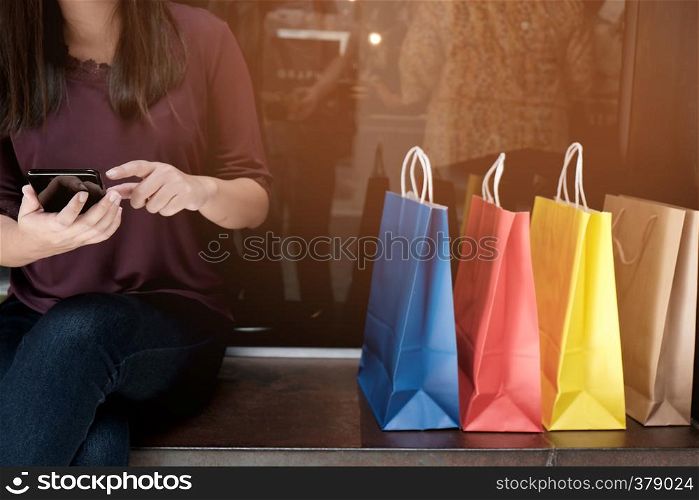 Asian girls holding sale shopping bags. consumerism lifestyle concept in the shopping mall hands holding cell telephone blank copy space screen