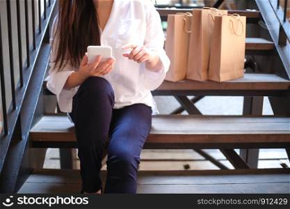 Asian girls holding sale shopping bags. consumerism lifestyle concept in the shopping mall hands holding cell telephone blank copy space screen