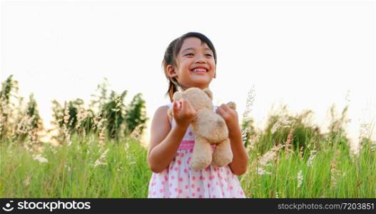 Asian Girls playing teddy bears and laughing happy on meadow in summer in nature