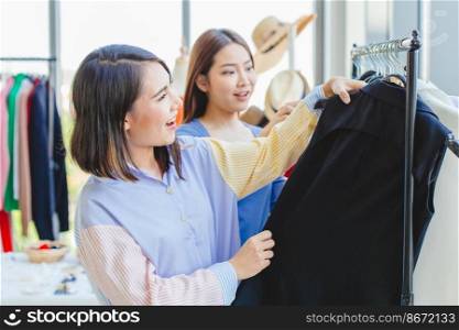 Asian girls teen enjoy shopπng to se≤ct≠w cloth with friend in fashion shop like black color cloth.