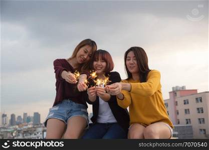 Asian group of friends lighting sparklers and enjoying freedom at sunset,asian woman holding sparklers happily on rooftop
