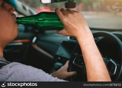 Asian guy with drunk alcohol, drinking beer while driving on the road.