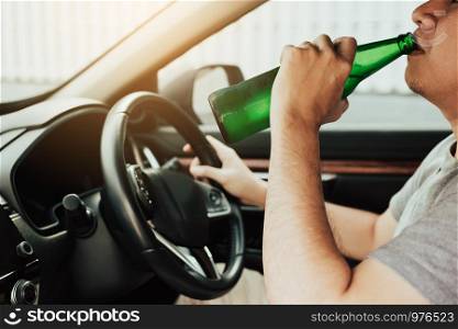 Asian guy with drunk alcohol, drinking beer while driving on the road.