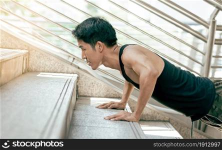 Asian handsome and healthy man doing exercise by pushing up stairs outdoor. Sport and Lifestyle Concept.