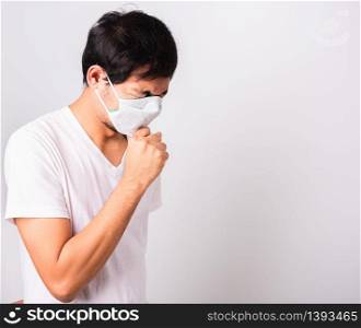 Asian handsome Man wearing surgical hygienic protective cloth face mask against coronavirus he sneeze hand close mouth, studio shot isolated white background, COVID-19 medical concept