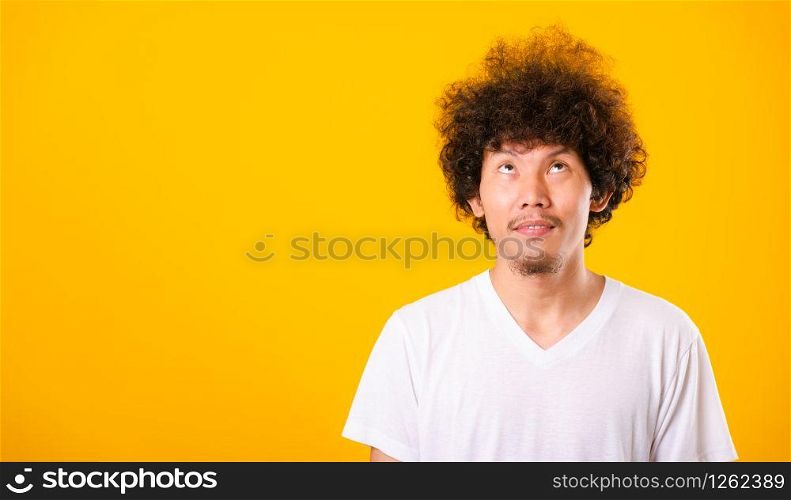 Asian handsome man with curly hair looking up see he hair isolate on yellow background with copy space for text