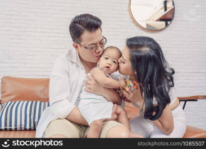 Asian Happiness family scene of parent are kissing the boy baby in the living room of house,Family Lifestyle Concept