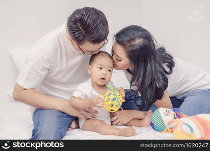 Asian Happiness family scene of parent are kissing the boy baby in the bedroom of house,Family Lifestyle Concept