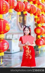 Asian Happy little girl wearing red traditional Chinese cheongsam decoration holding red envelopes in hand and lanterns with the Chinese text Blessings written on it Is a Fortune blessing for Chinese