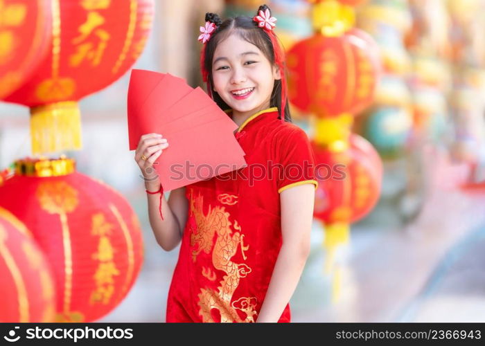 Asian Happy little girl wearing red traditional Chinese cheongsam decoration holding red envelopes in hand and lanterns with the Chinese text Blessings written on it Is a Fortune blessing for Chinese