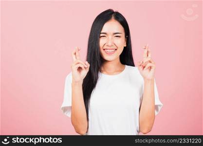 Asian happy portrait beautiful cute young woman smile have superstition her holding fingers crossed for good luck gesture studio shot isolated on pink background, Thai female with copy space